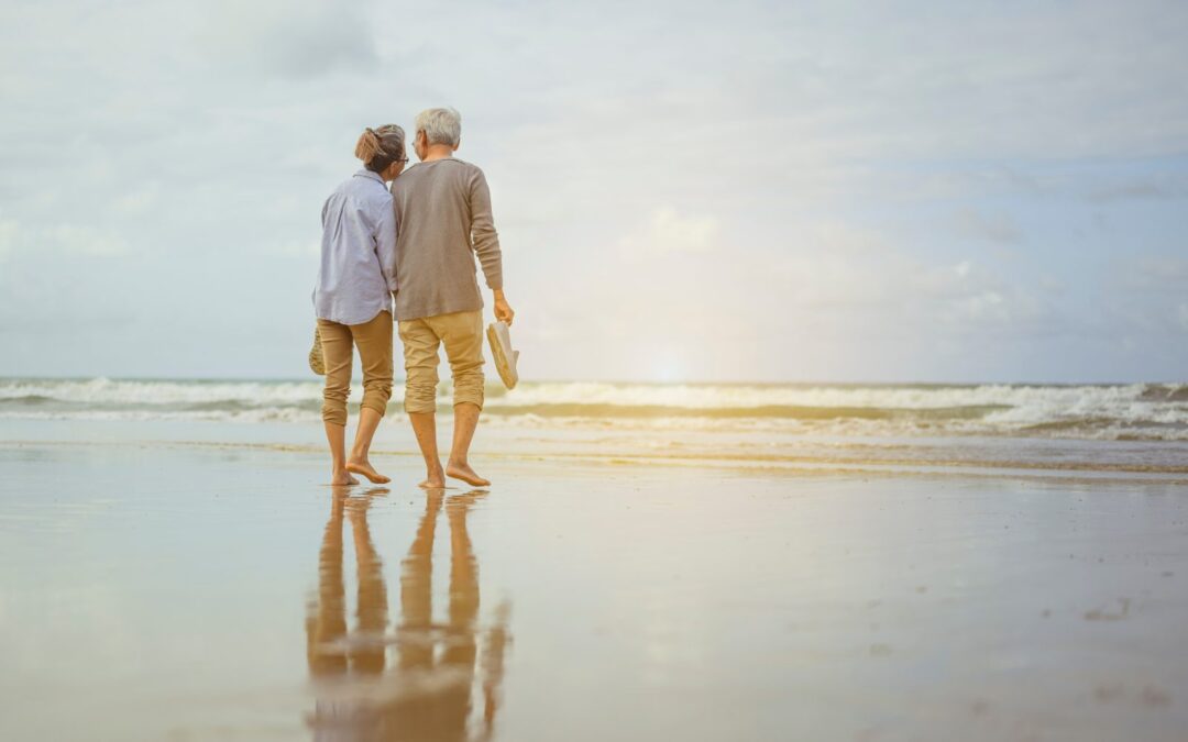 Pareja de jubilados paseando por la playa: seguro de decesos al vivir en el extranjero
