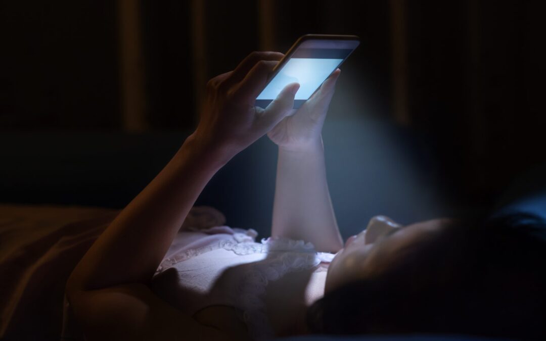 Persona con el móvil de noche: llamar al teléfono de asistencia del seguro de decesos